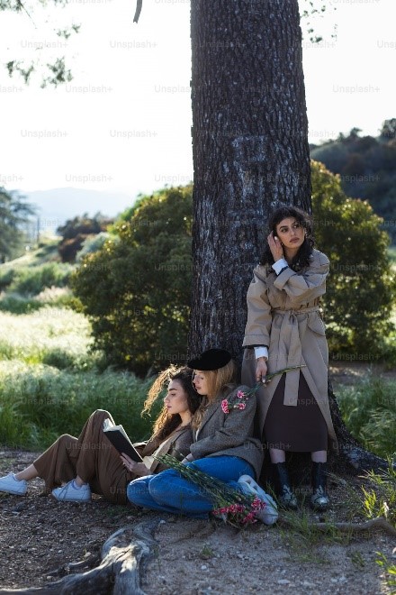 Three women lean on a tree to read